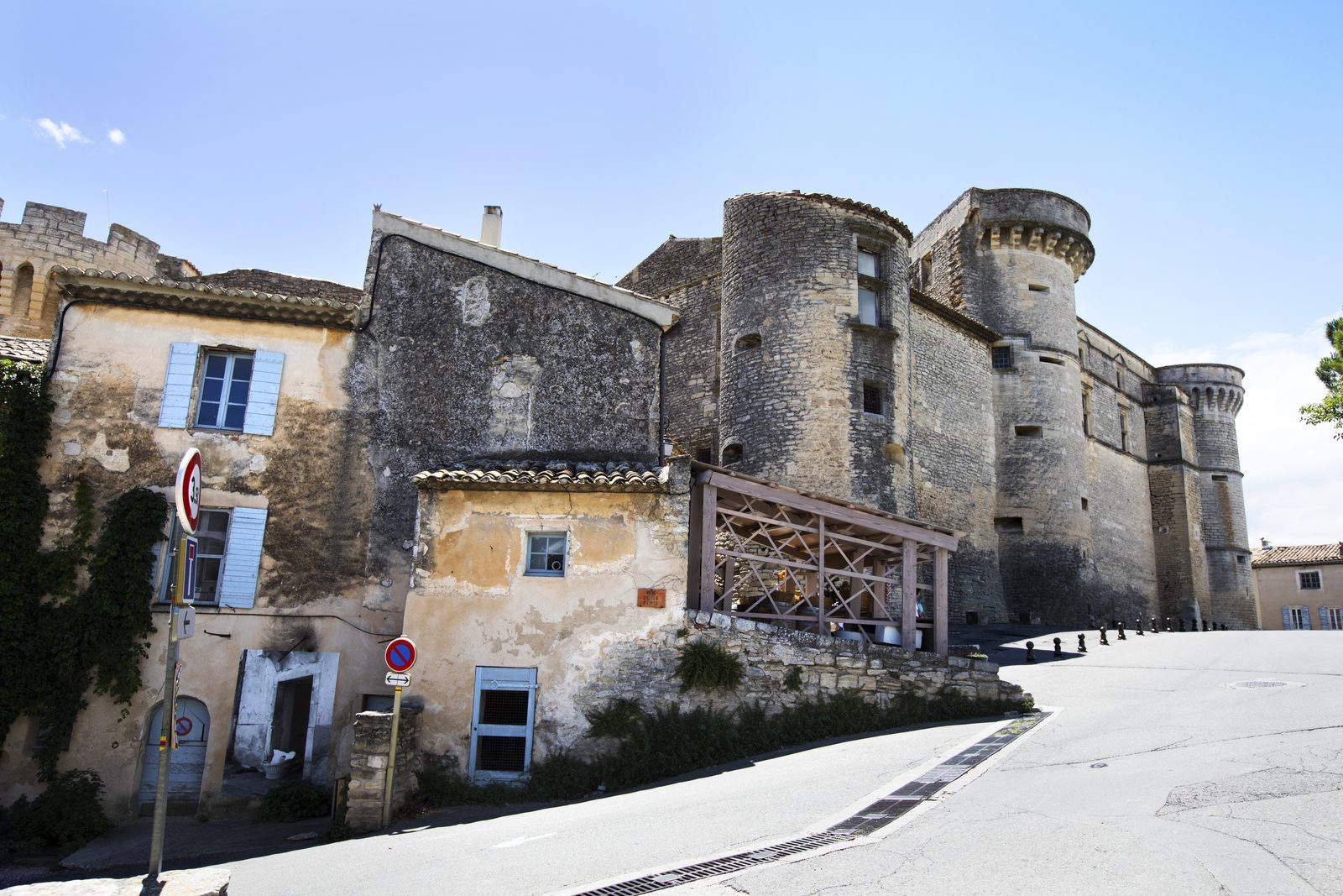 The medieval Château de Gordes, with two stone towers and a sand-coloured stone facade, against a clear blue sky